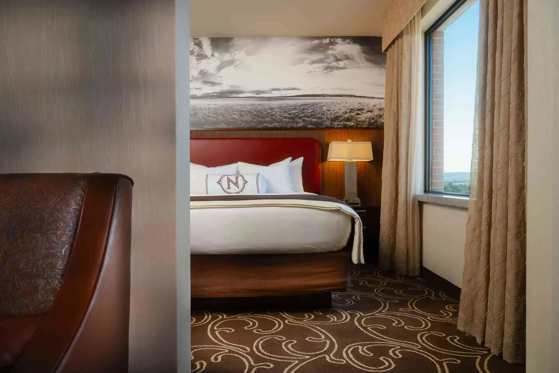 Deluxe suite with armchair seating, work desk, and large windows over downtown Billings